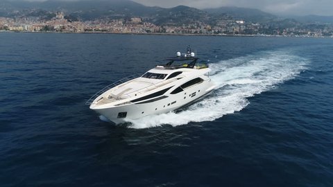 Aerial lateral view of a luxury yacht navigating slowly close to the Ligurian coast
