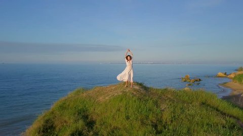 Happy healthy romantic woman circling around on top coast sunrise drone footage