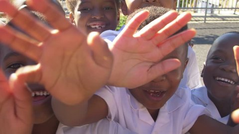 Young school kids in playground waving to camera, close up