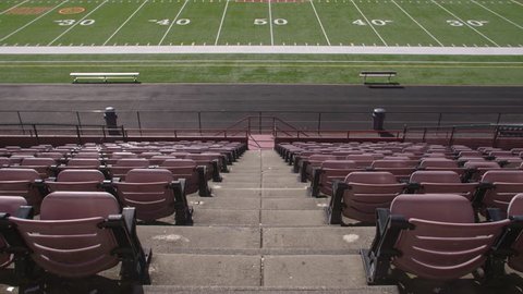 Empty rows of chairs in a high school football stadium from above, looking down on the field  库存视频