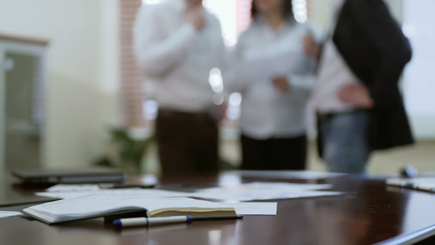 Employee joining colleagues in group discussion over report papers in a meeting