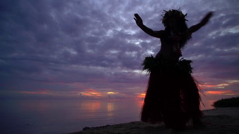 Beautiful young synchronized Polynesian female dancing on the ocean beach at sunset in traditional costume barefoot French Polynesia South Pacific