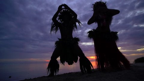 Young male and female Tahitian hula dancers performing at sunset on ocean beach barefoot in traditional costume Tahiti South Pacific