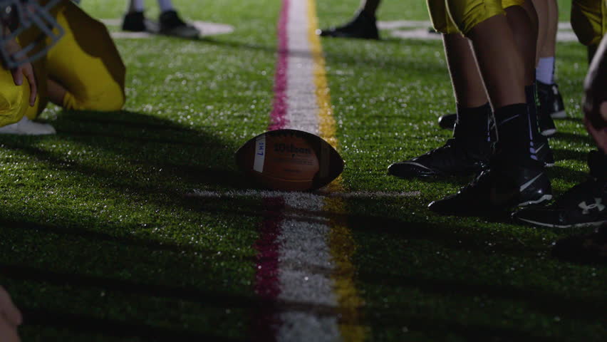 Close up of a football, as players get set at the line of scrimmage Royalty-Free Stock Footage #28066582