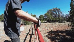 VALLE AZ/USA: April 18, 2017- High angle view of a man painting a fence on a ranch. Clip provides a view into physical labor chores and maintenance required on off grid land property in the country.