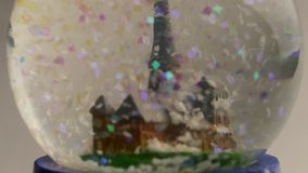 Ungraded: Christmas snow globe with colorful artificial snowflakes falling near old european cathedral. Source: Lumix DMC, ungraded H.264 from camera without re-encoding. (av36853u)