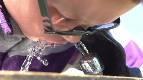 boy drinks from water fountain in slow motion