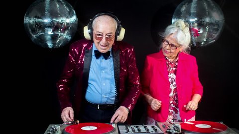 Amazing DJ grandma and grandpa, older couple djing and partying in a disco setting. these retired rockers will get the party going.