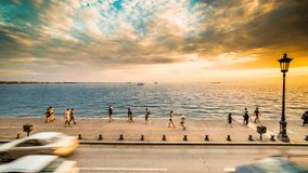 Golden Sunset Clouds, Tranquil Sea, People Walking and Cars Traffic on the road of Thessaloniki Port near the sea, Timelapse 