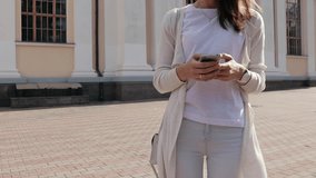 Close-up of a young woman enjoying a mobile phone in the city in summer, slow motion