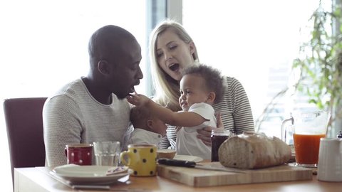 Young interracial family with little children having breakfast.