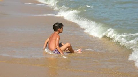 Young boy playing in the waves on the tropical sea