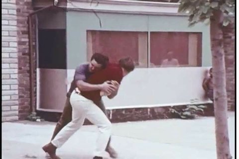 1970s: Police officers increase the tension in a fight between two men outside of a bar, and police officers reduce tension in a fight between two men outside of a bar in the 1970s.