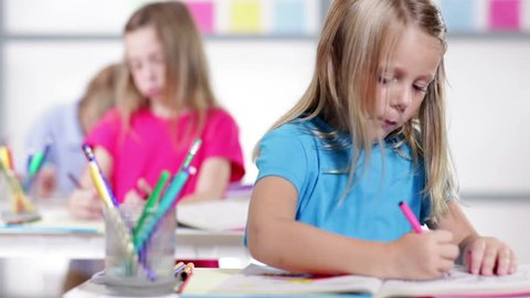 A cute little girl in a classroom setting works diligently on her school task.