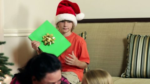 A mother smiles as her little daughter rattles a Christmas gift box to try and guess what is in it.