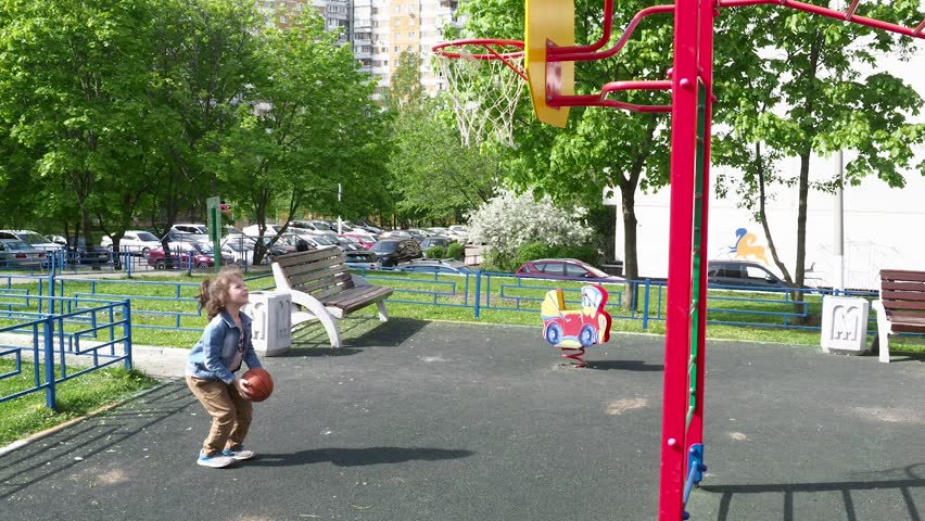 The boy throws the ball into the basketball ring.