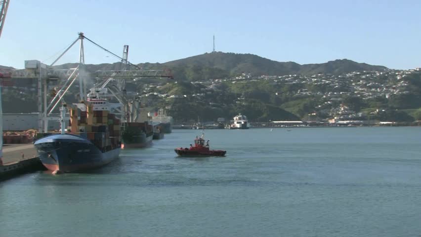 Welington, New Zealand, October 2011. Cruising past the commercial port facility of Wellington with Container ship ready for departing and being assisted by tug boat