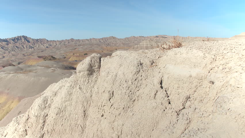 Young female tourist exploring Badlands National park, reaching the top and admiring the view of pointy sandstone mountains. Cheerful woman traveler on a journey across the States trekking rocky hills