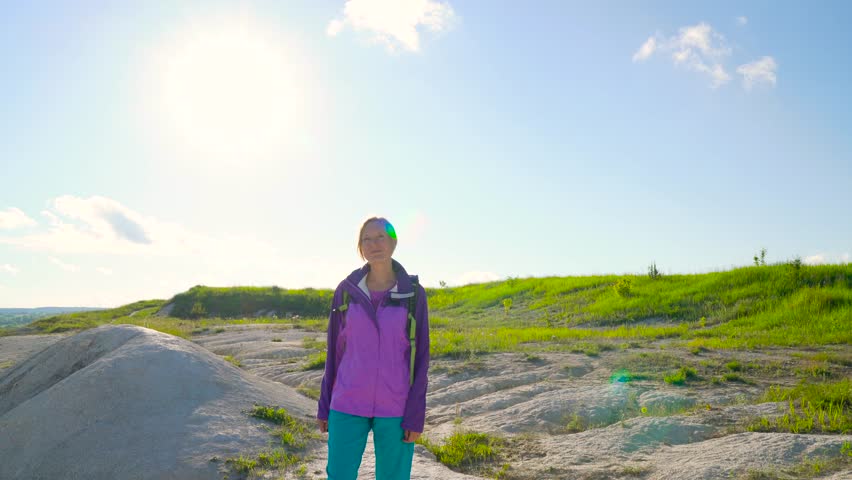 Woman is traveling with a backpack over hilly terrain. Hiking