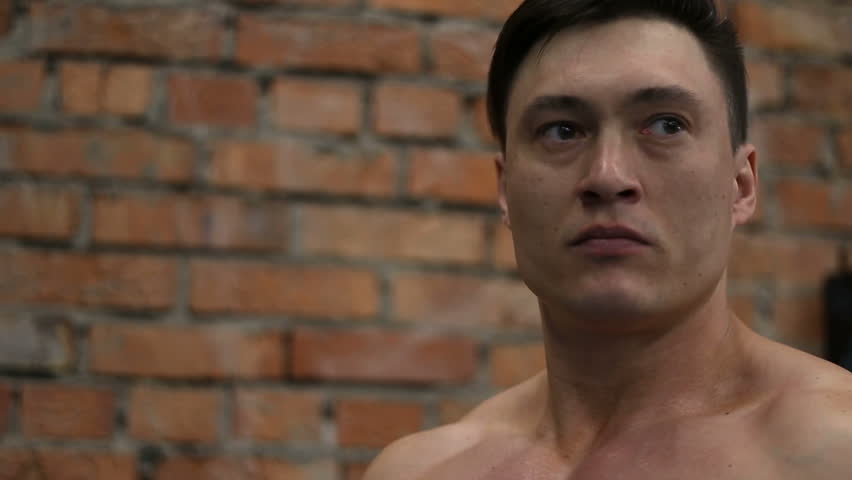 Muscular man drinking water after grueling workout