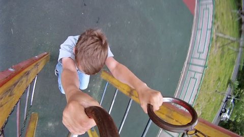 Boy hang on sports rings at playground in house yard Stock Video