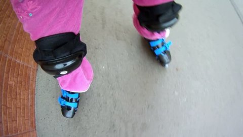 Little girl rollerblading on paved road near brick wall Stock Video