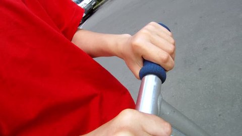 Boy in red T-shirt strong keeps in hands a scooter helm