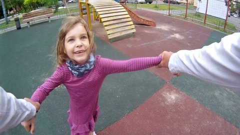 Father twist the daughter by hands at playground in house yard