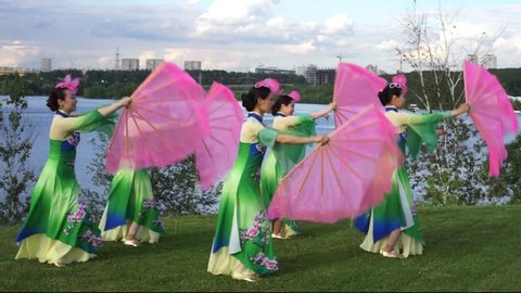 group of five asian women actresses in traditional chinese costumes with fans dancing at the riverbank outdoor