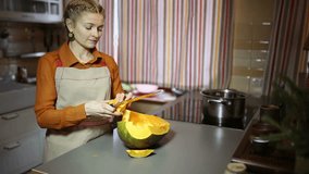 Woman carefully cuts a pumpkin