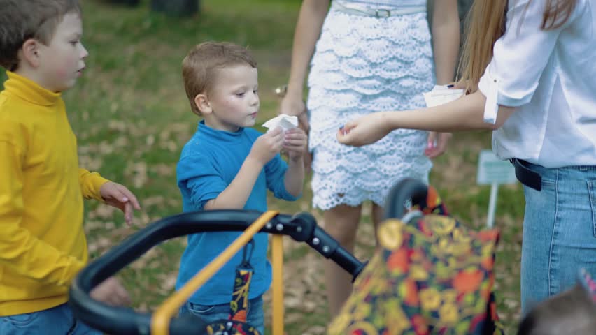 Little children wipe their faces with napkins after playing in the park. 