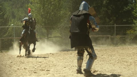 Knight rider on horseback spearing medieval armored warrior with jousting spear