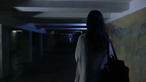 Scared woman screaming in dark underpass at night