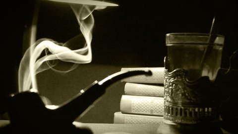 Sepia footage of a 1930's office: smoking pipe, tea and a stack of books
