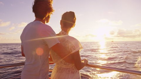 Cruise ship - Romantic couple enjoying sunset over the ocean on small cruise ship sailing on open sea. Woman and man in love on boat travel sailing during vacation. 