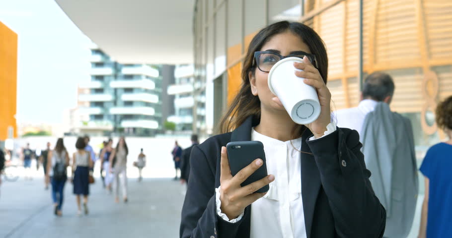 Portrait of a young beautiful business woman (student) in a suit, glasses, walking around the city, drinking coffee, talking on the phone. Concept: new business, communication, Arab, banker, manager. Royalty-Free Stock Footage #28148473