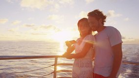 Couple using smart phone screen on sunset cruise ship sailing in ocean on vacation. Woman and man looking at smartphone app having fun on travel.