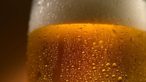 Cold Light Beer in a glass with water drops. Craft Beer close up. Rotation 360 degrees. 4K UHD video 3840x2160