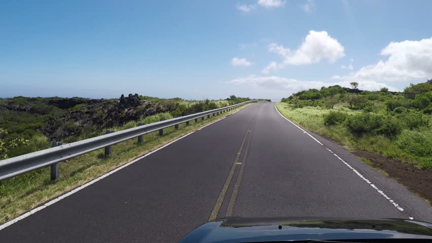 Lonely and remote winding road past Hana around south of Maui along the coastline with wind turbines