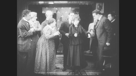 1910s: Woman faints while talking, man behind her looks stunned. Another man enters the room and everyone flees. Young woman regains consciousness and everyone looks relived.