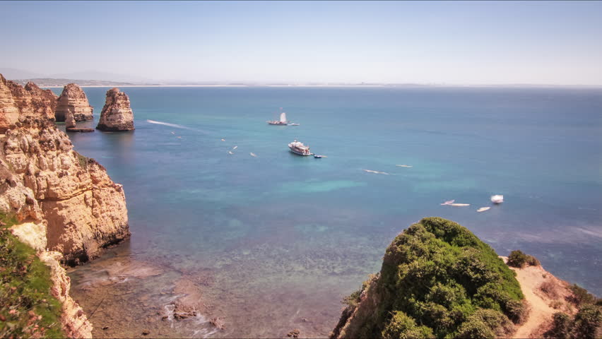 Rocky sea shore and sailing ships. Time lapse of cruise ships swimming in calm water. Sail ships at sea. Panoramic view sailing ships at sea
