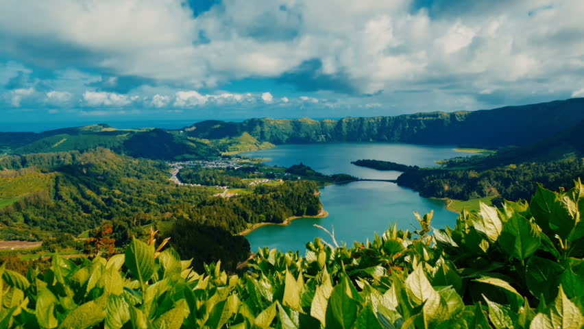 Establishing shot of the famous Lagoa das Sete Cidades lake seen behind green vegetation, in Sao Miguel, The Azores, Portugal