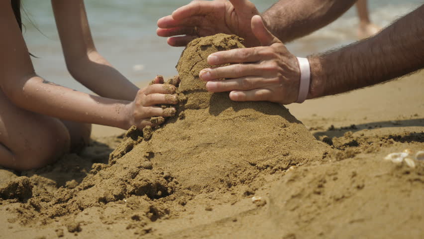 Building sand castle. Family playing on the beach building sand castle.
