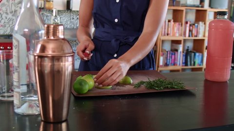 Woman slicing limes preparing to make cocktail mocktails in trendy apartment