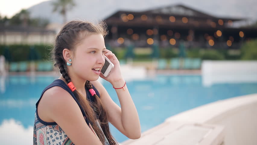 Young girl by the pool talking on the phone
