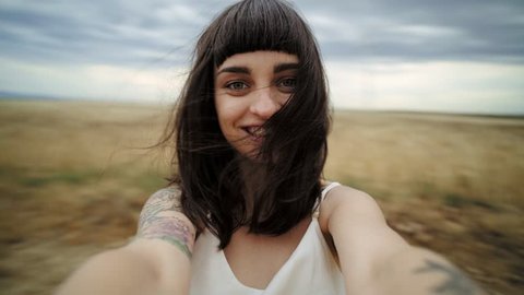 Portrait of attractive natural happy young brunette female spins around in middle of field during advneture vacation journey through national park, concept freedom, youth, integrity, eco consciousness