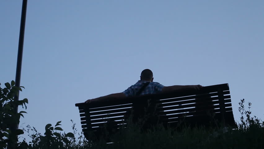 People sitting on bench and walking down. Low angle full shot horizontal pan.