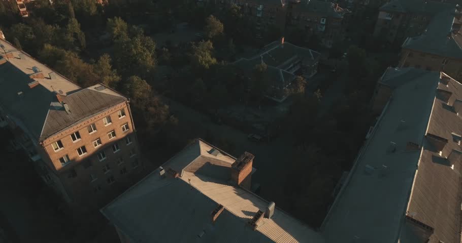 Urban landscape of the old city, aerial. Cityscape of Kiev from above. Summer evening, sunset, houses, roads and cars. People walk on the sidewalk. Green trees in the city quarter.
