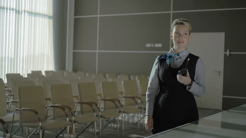Pretty woman talks to the walkie-talkie in the conference hall