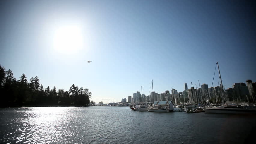 Waterplane flying through the sun over the Vancouver False Creek Marina near